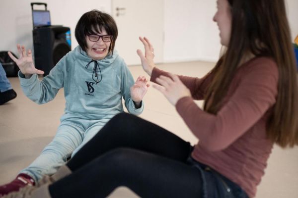 Ein Mädchen und eine junge Frau sitzen auf dem Boden und lachen