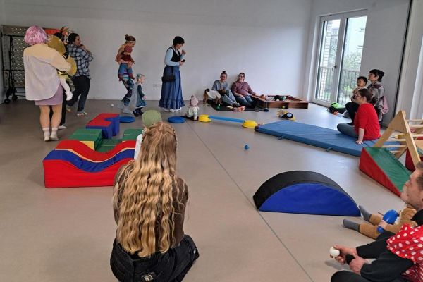 Mehrere Eltern spielen und toben mit ihren Kindern