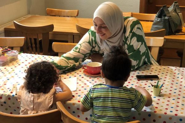 Eine Ehrenamtliche spielt mit 2 Kindern während des Offenen Treffs