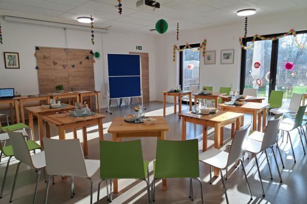 Ein leerer Raum, in dem Tische und Stühle im Kreis stehen. Vorbereitet für einen Kurs.